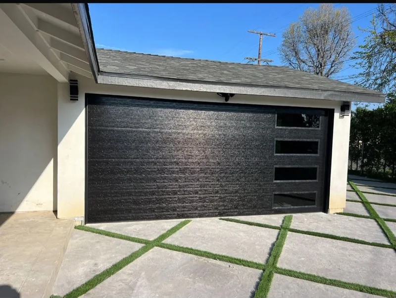 Dark textured garage door with three windows along one side.