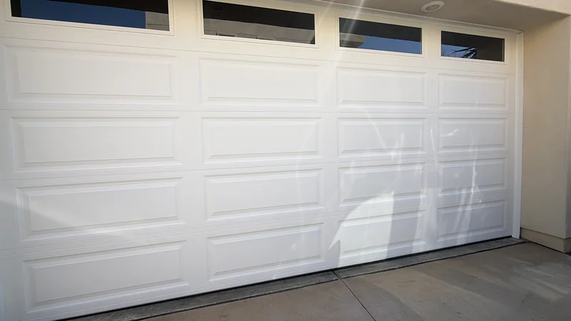 White garage door with long rectangular panels and narrow top windows.
