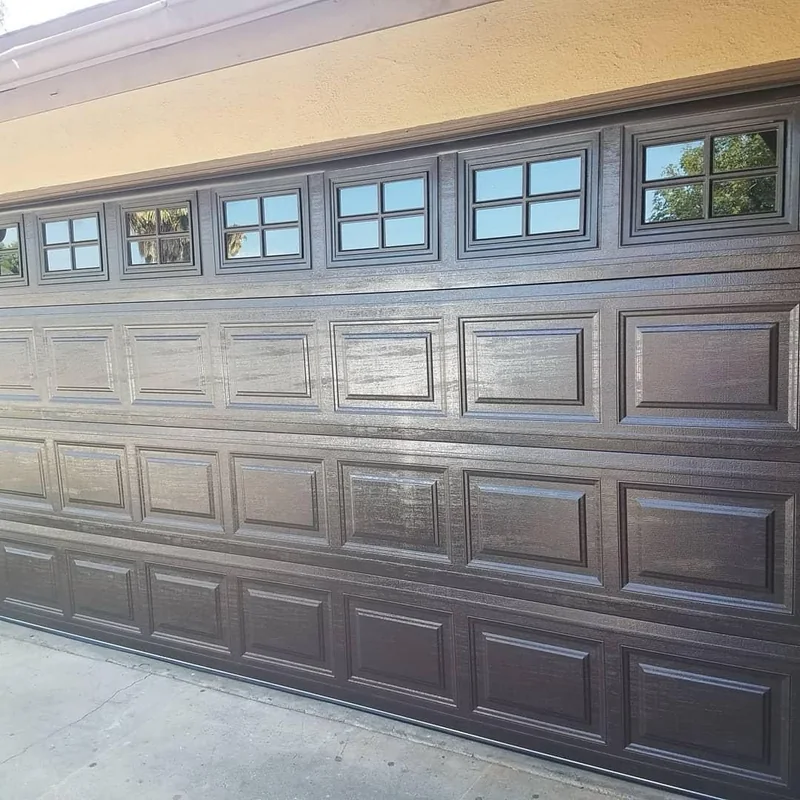 Dark raised-panel garage door with divided windows along the top.